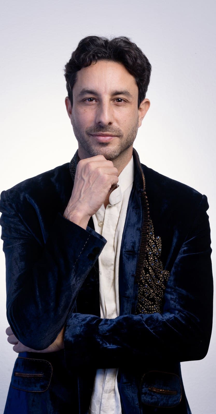 Lukaijah in a velvet embroidered jacket, fist to chin